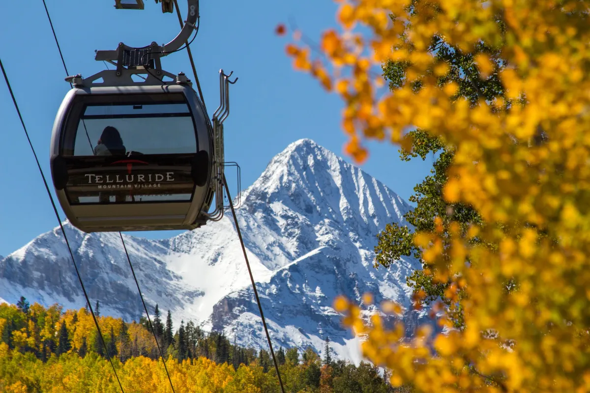 This image features a gondola lift gliding over snow-capped mountains and vibrant autumn foliage, perfectly capturing Telluride’s renowned outdoor recreation and breathtaking alpine scenery. The landscape radiates adventure and year-round appeal, seamlessly aligning with skiing, hiking, and sightseeing activities mentioned in the section.