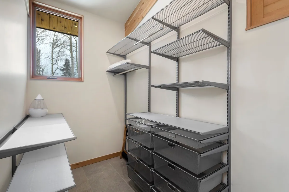 Shows a well-organized storage room with metal shelving units, drawers for stashing equipment, and a window allowing in natural light. The mood is efficient yet calm, emphasizing order and readiness.